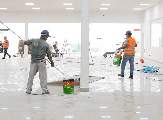 Aplicação de revestimento no piso Trabalhadores aplicando revestimento no piso durante obra